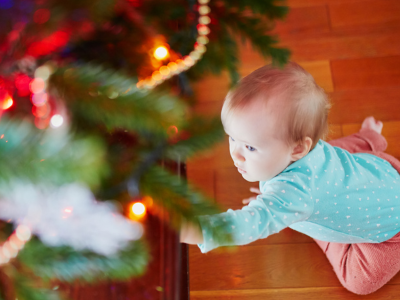 Kind unter dem Christbaum, greift nach einem Zweig